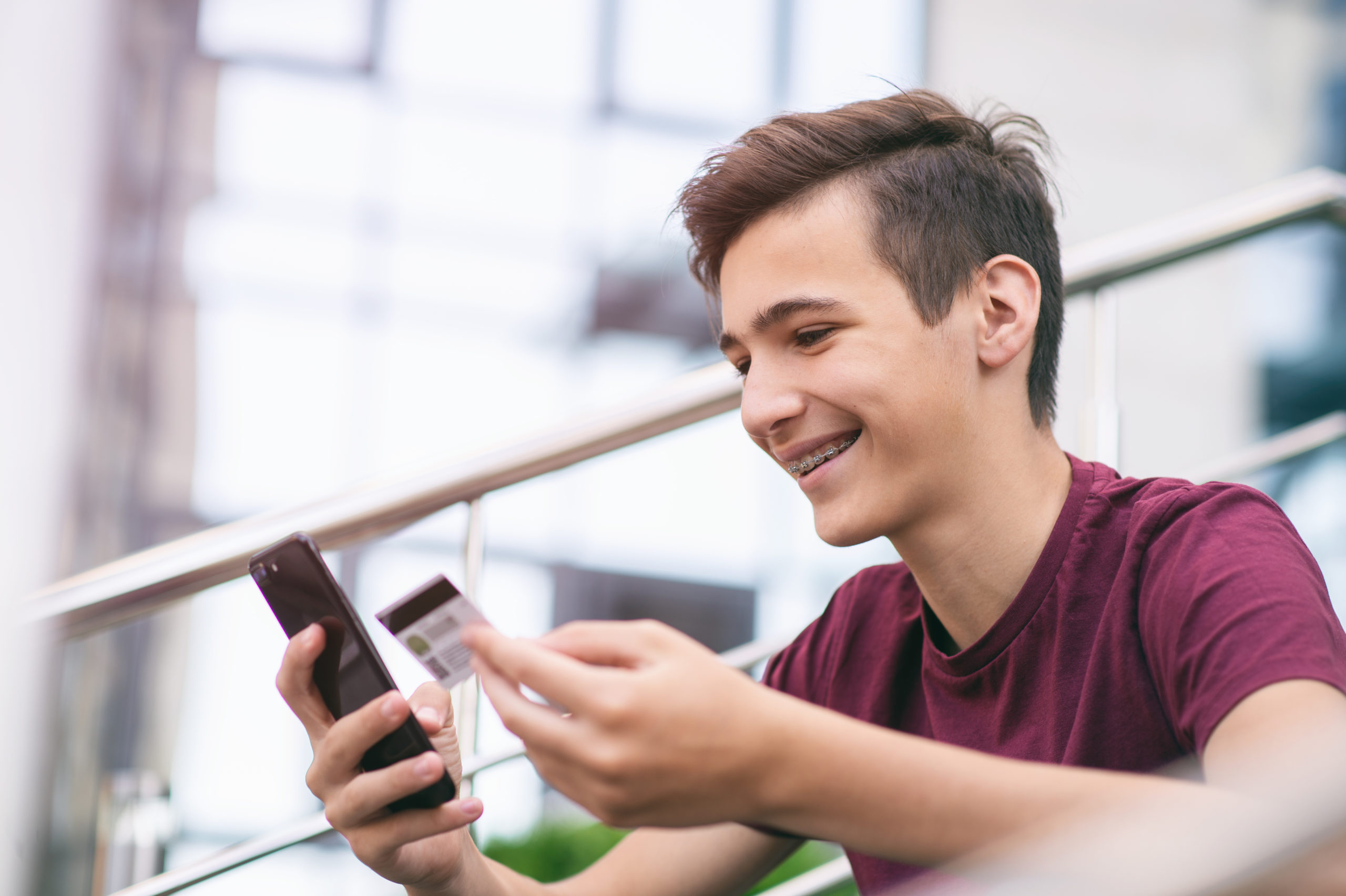 Teenage boy with a credit card and mobile phone makes purchasing